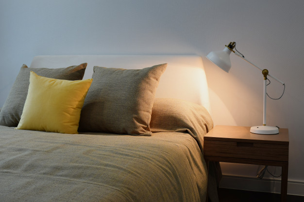 cozy-bedroom-interior-with-pillows-reading-lamp-bedside-table_65102-68