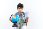 concerned-little-schoolboy-wearing-back-bag-headphones-holding-tickets-globe-isolated-white-background